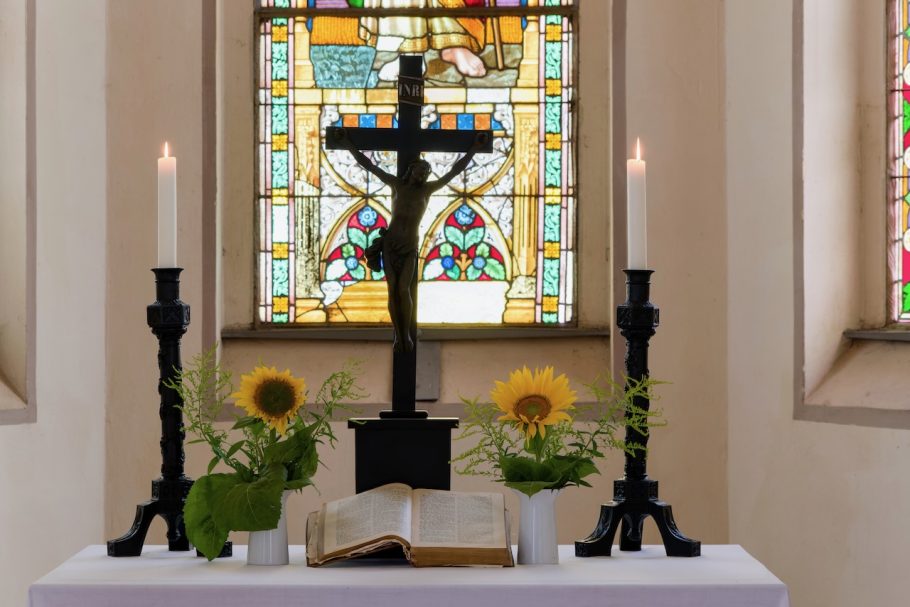 Ein Altar mit einer Kreuzigung, Kerzen, Sonnenblumen und einer geöffneten Bibel.