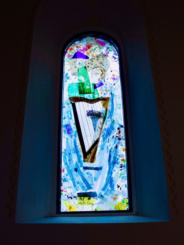 Buntes, modernes Kirchenfenster mit abstrakten Formen und lebhaften Farben.