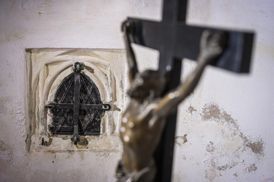 Kruzifix mit einem historischen Fenster im Hintergrund.