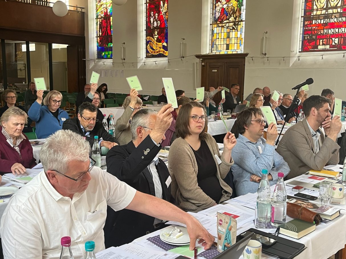 Die Versammlung hebt Abstimmungszettel zur Abstimmung über ein Thema.