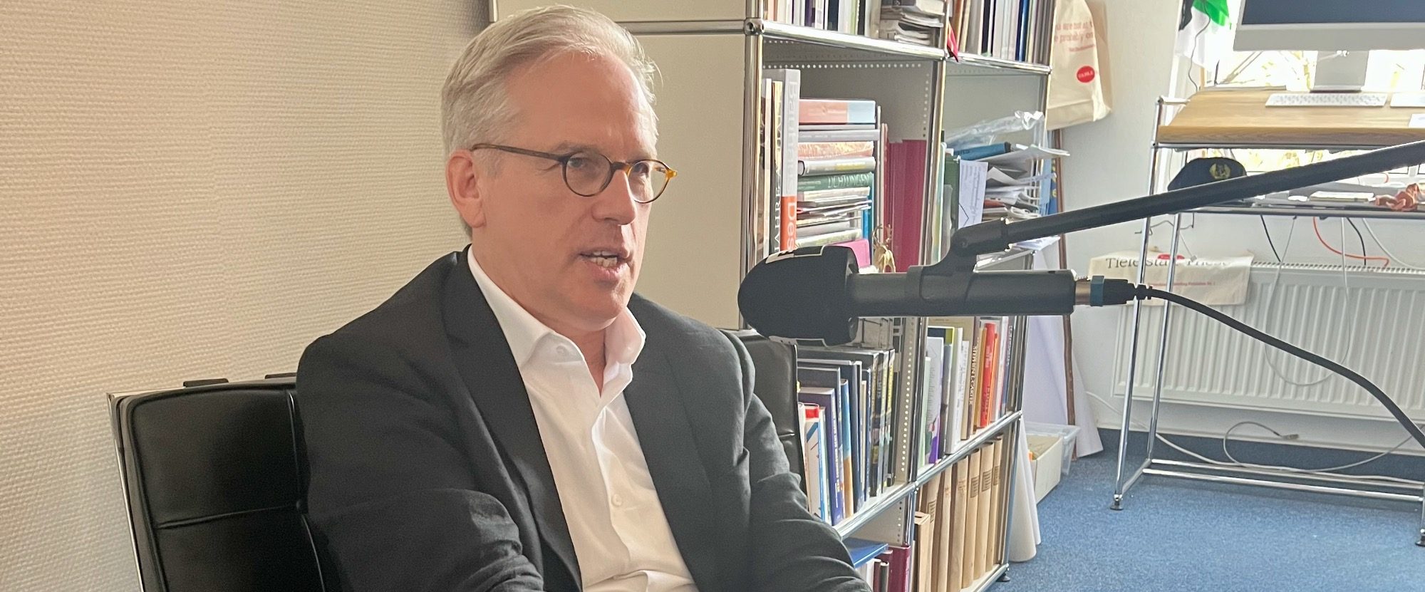 Menschen bilden einen Kreis auf einer Wiese, umgeben von Bäumen und Gebäuden.