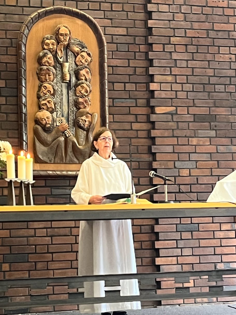 Eine Person in einem weißen Gewand steht vor einem Altar in einer Kirche.