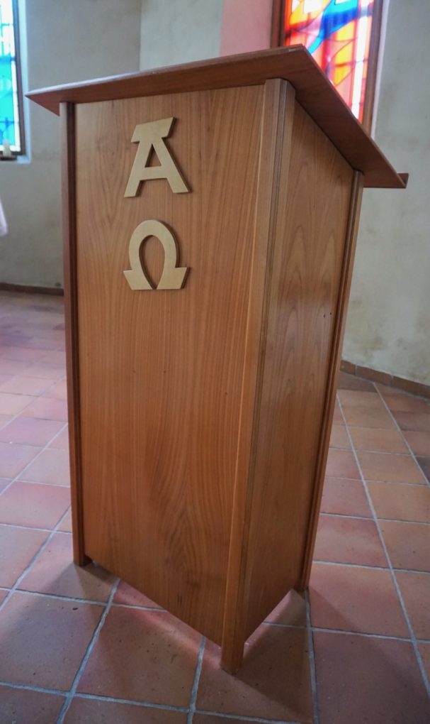 Holzrednerpult mit den griechischen Buchstaben Alpha und Omega auf der Vorderseite.