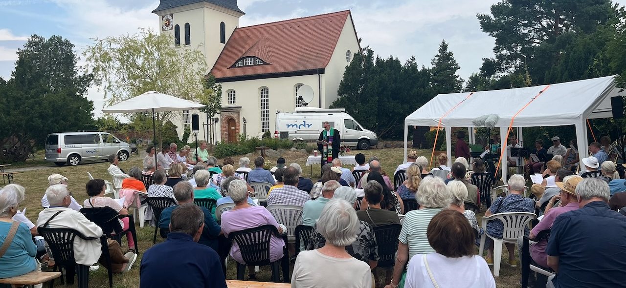 Proben einer Theateraufführung mit Schauspielern und Musiker:innen auf der Bühne.