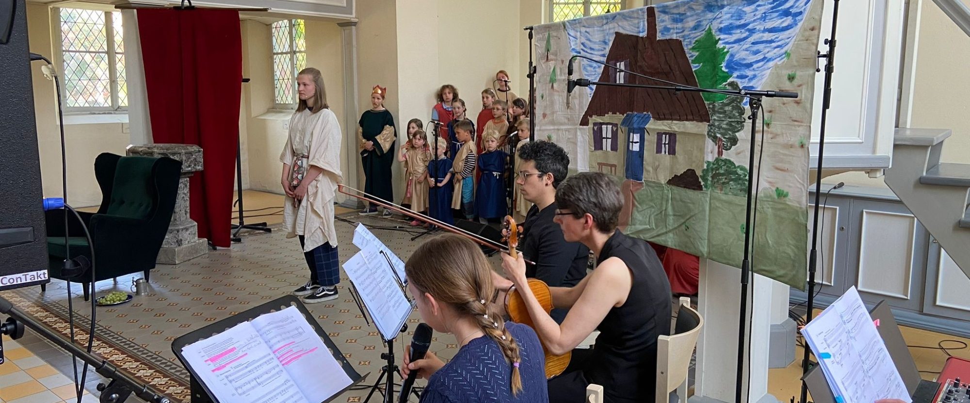 Proben einer Theateraufführung mit Schauspielern und Musiker:innen auf der Bühne.