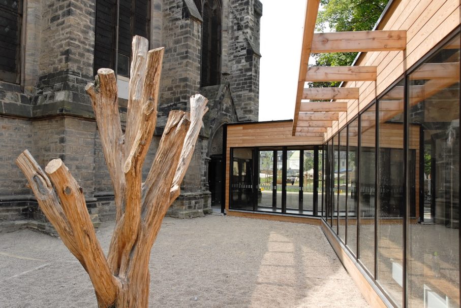 Moderne Architektur mit Holzdetails, angrenzend an eine historische Kirche.