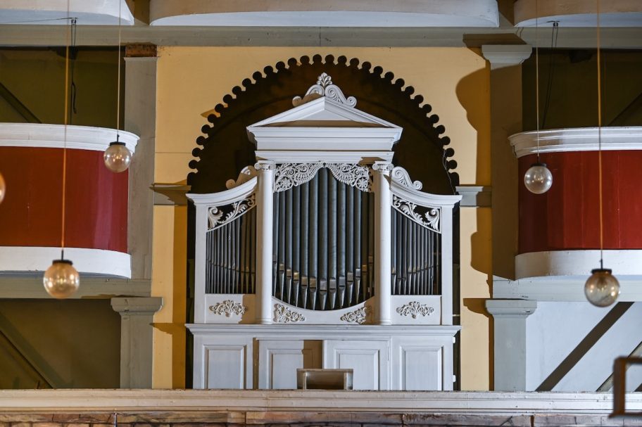 Historische Orgel mit weißen und roten Ornamenten in einem Kirchenraum.